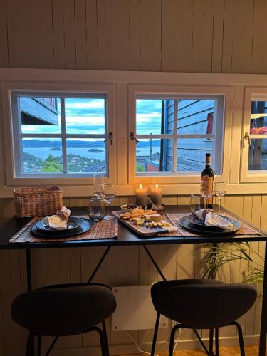 stół z dwoma krzesłami i jedzeniem oraz dwa okna w obiekcie The View Guesthouse at Ekeberg -10 min by tram to Oslo S w Oslo