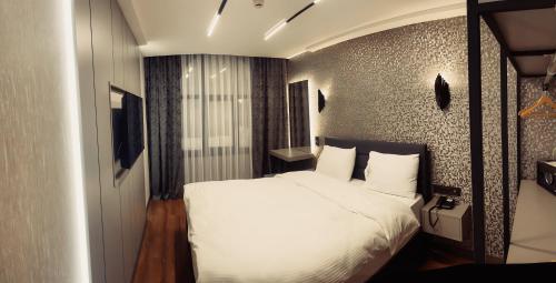 a bedroom with a bed with white sheets and pillows at Uzunkum Hotel in Trabzon