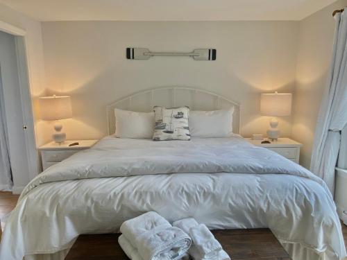 een slaapkamer met een wit bed en handdoeken bij Seaside Inn in Tenants Harbor