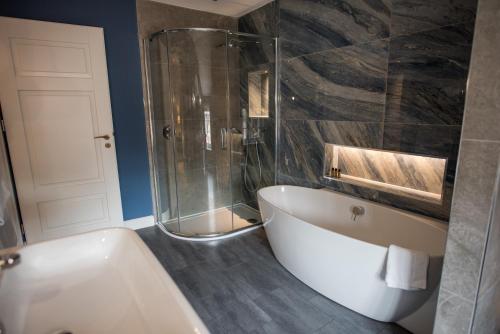 a bathroom with a tub and a glass shower at Dewars Restaurant and Rooms in Malton