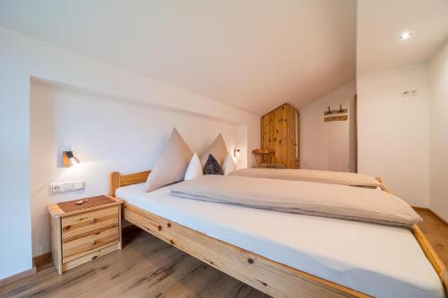 een slaapkamer met een groot bed en een houten nachtkastje bij Alpenhaus Thurnher in Gaschurn