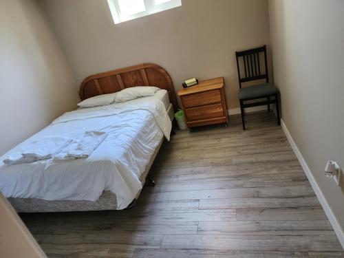 1 dormitorio con 1 cama, 1 silla y suelo de madera en Economical Homestay en Burnaby