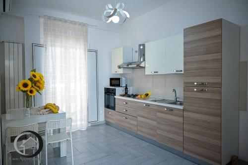 une cuisine avec des placards en bois et un vase de tournesols dans l'établissement CAOS, à Bari