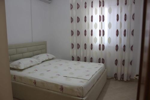 a bedroom with a bed and a window with curtains at Malaj's Rooms in Sarandë