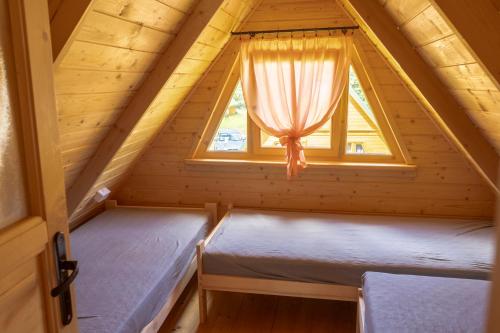 two beds in a tiny house with a window at Nad Strumykiem in Sasino