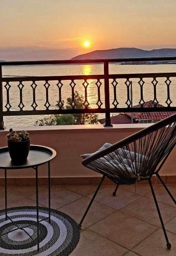 a chair and a table on a balcony with a sunset at Mary's Luxury Apartment in Agria
