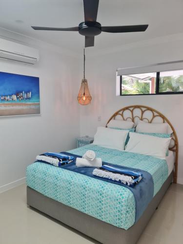 a bedroom with a large bed with a fan at Blue Lagoon Tropical Sanctuary in Trinity Beach