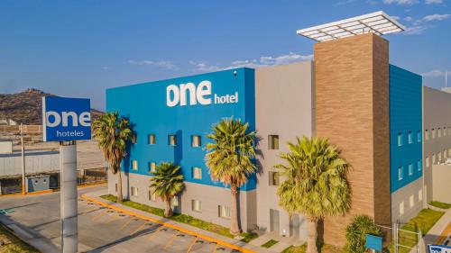 a one hotel building with palm trees in front of it at One Saltillo Aeropuerto in Saltillo