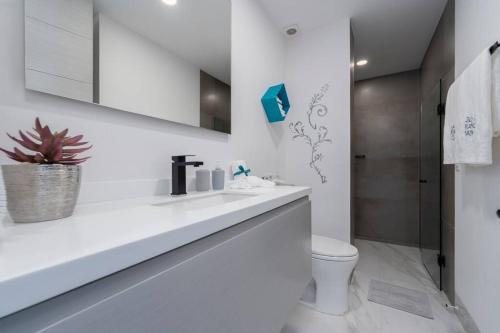 a white bathroom with a toilet and a sink at Casa Sueño - Modern, spacious & luxurious brand new condo in Cabo San Lucas