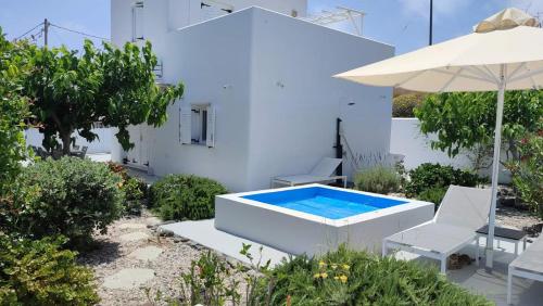 a pool in the middle of a garden with chairs and an umbrella at JB Villa in Mesaria