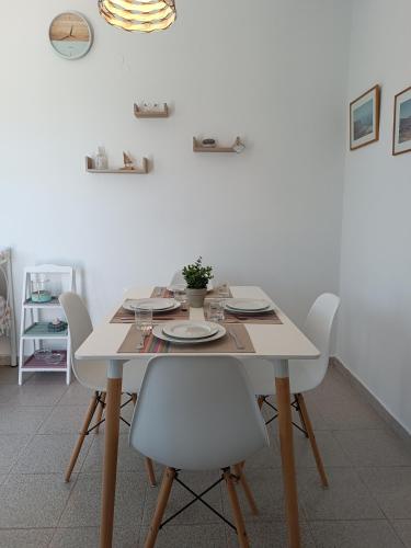 a dining room table with white chairs and a white wall at Thea Nisaki Mochlos in Mochlos