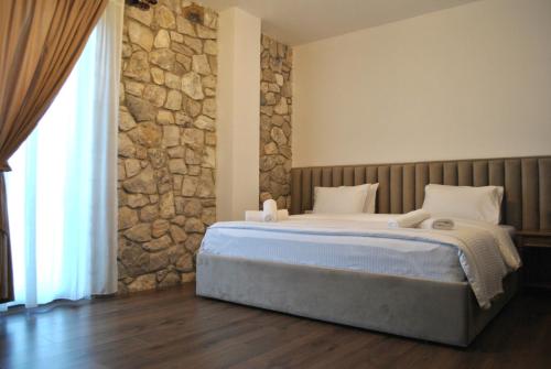 a bedroom with a large bed with a stone wall at Boutique Vila FIDANI in Voskopojë