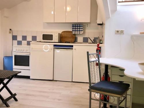 a kitchen with white appliances and a table and a chair at cosy small FLAT in Antwerp near Justice Palace in Antwerp