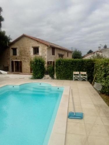 une grande piscine bleue devant une maison dans l'établissement Les Vents d’Anges, à Clussais-la-Pommeraie