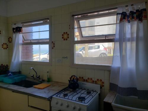 cocina con fogones y fregadero y 2 ventanas en Departamento frente al mar en Mar del Plata