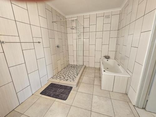 a white tiled bathroom with a shower and a sink at Dagha Boys in Khwai