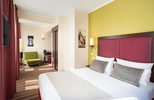 - une chambre avec un grand lit et une tête de lit rouge dans l'établissement Leonardo Hotel Berlin, à Berlin