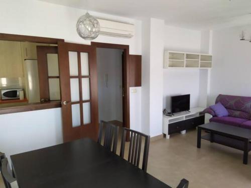 a living room with a table and a purple couch at Apartamentos Centro El Rompido in El Rompido