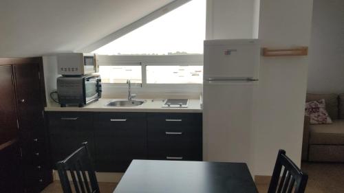 a kitchen with a sink and a microwave and a table at Apartamentos Centro El Rompido in El Rompido