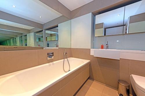 een grote badkamer met een bad en een wastafel bij Cosy Apartment in Central London in Londen