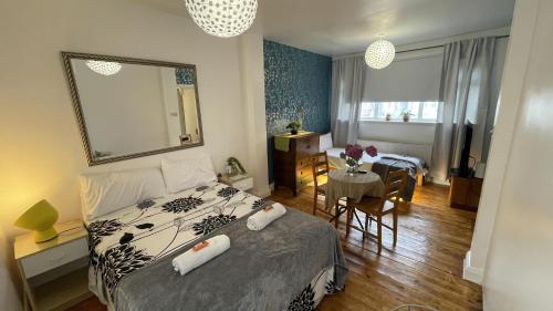 a bedroom with a bed with a mirror and a table at Lovely flat near train station and central london in London