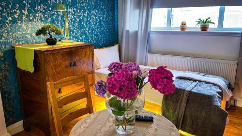 a room with a vase of purple flowers on a table at Lovely flat near train station and central london in London