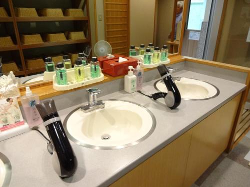 a bathroom counter with two sinks and a mirror at Natsukashiya Fuwari in Nikko