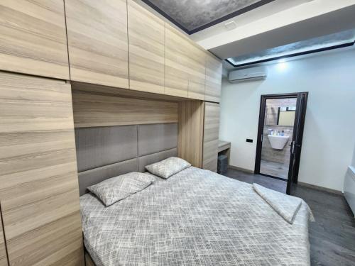 a bedroom with a large bed with a wooden wall at DELUXE Modernly Renovated 2 Bedroom + 2 Bathroom Apt by REPUBLIC SQUARE in Yerevan