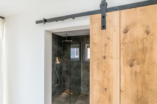 La salle de bains est pourvue d'une douche et d'une porte coulissante en bois. dans l'établissement Fika, à Renesse