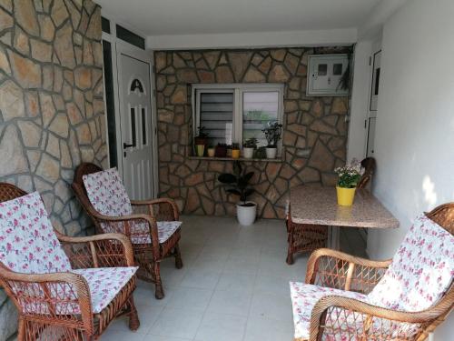 een patio met stoelen, een tafel en een stenen muur bij Bevanda in Široki Brijeg