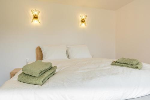 a white bed with two green towels on it at Fika in Renesse