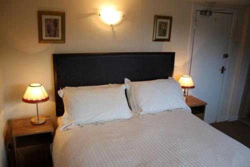 a bedroom with a large bed with two lamps on tables at Highland House Callander in Callander