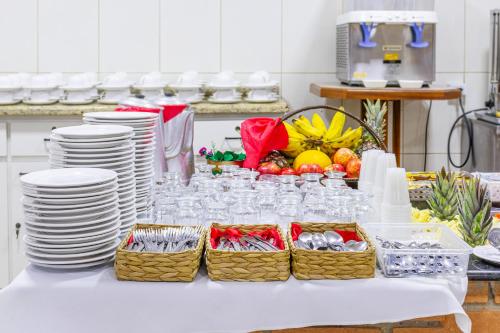 uma mesa com pratos, copos e cestas de comida em Hotel Caminho do Rosário em Aparecida