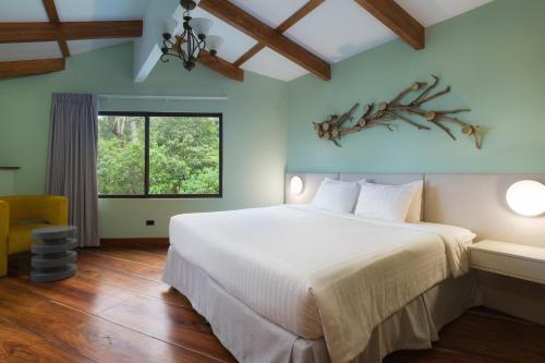 Un dormitorio con una gran cama blanca y una ventana en Koora Monteverde-a Cloud Forest Hotel by Sandglass en Monteverde