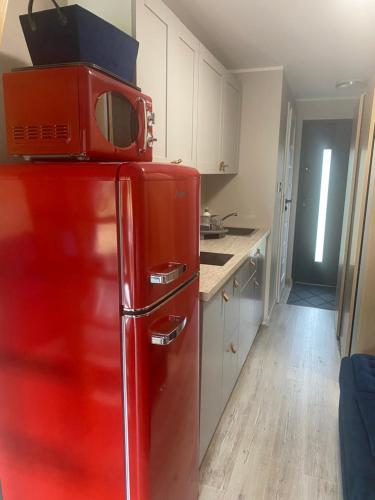 czerwona lodówka z kuchenką mikrofalową na górze w obiekcie Domek ,, Daglezja ” w Dziwnowie