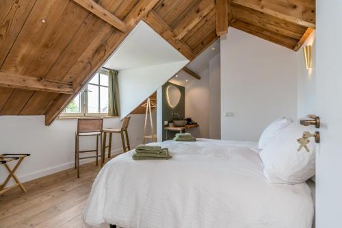 a bedroom with a white bed and wooden ceilings at Fika in Renesse