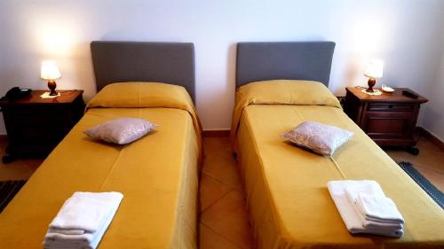 two beds in a room with yellow sheets and pillows at Palazzo Zimatore Residenza D'Epoca in Pizzo
