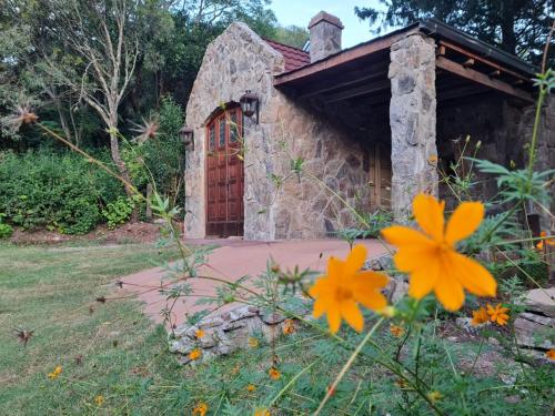 un edificio de piedra con una puerta en un patio con flores en Casita de Piedra B&B en Villa del Dique