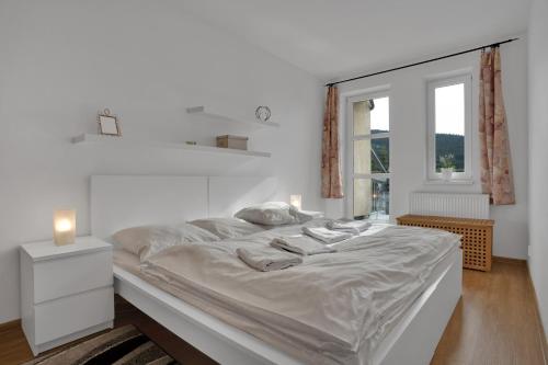 um quarto branco com uma cama grande e uma janela em Horský Apartmán Klínovec 4 em Loucná pod Klínovcem
