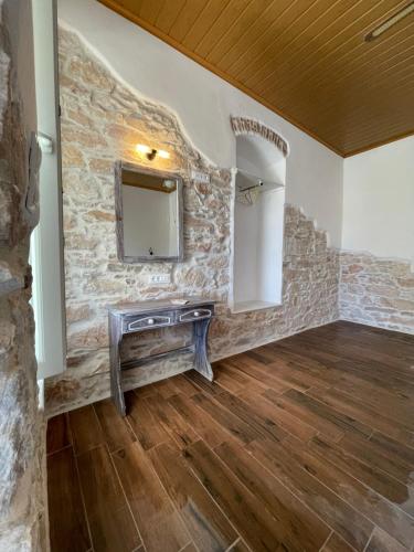Una habitación con una pared de piedra con un tocador y un espejo. en KROISSOS, en Galissas