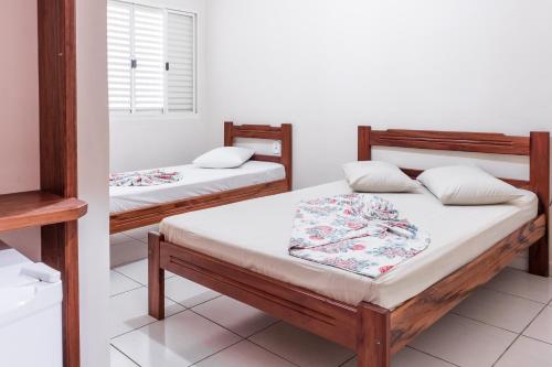 2 camas individuales en una habitación con ventana en Hotel Caminho do Rosário, en Aparecida