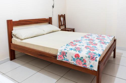 a bedroom with a bed with a floral quilt on it at Hotel Caminho do Rosário in Aparecida