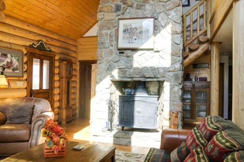 a living room with a stone fireplace in a log cabin at Lacys Log Cabin Alto Home with Mountain Views! in Alto