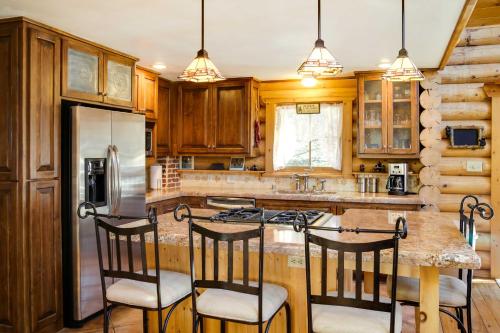 a kitchen with wooden cabinets and a island with bar stools at Lacys Log Cabin Alto Home with Mountain Views! in Alto