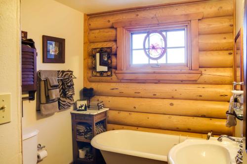 ein Badezimmer mit einer Holzwand mit einer Badewanne und einem Fenster in der Unterkunft Lacys Log Cabin Alto Home with Mountain Views! in Alto