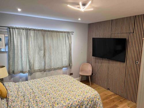 a bedroom with a bed and a flat screen tv at En-suite Double Room - Private Entrance & Free Parking in West Drayton