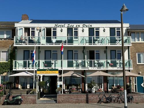 a building with tables and umbrellas in front of it at Hotel Zee en Duin in Katwijk