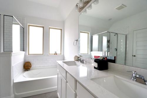 a white bathroom with a tub and a sink and a bath tubermott at Calming 4-bedroom with fireplace & game room in Little Elm