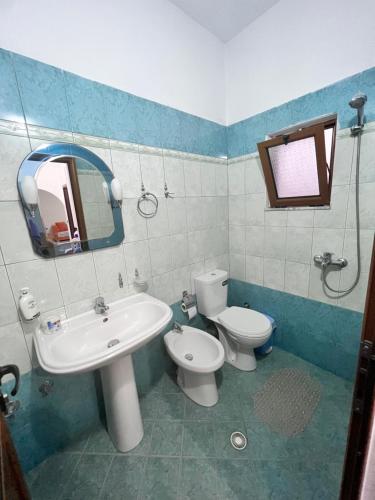 uma casa de banho com um lavatório, um WC e um espelho. em Kristina Apartament em Saranda