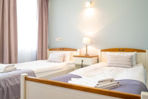 two beds in a hotel room with towels on them at Hotel Rozmaryn i Lawenda in Minikowo